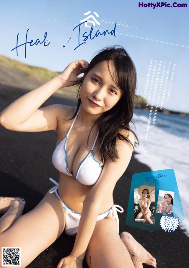 A woman in a white bikini sitting on a beach.