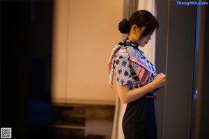 A woman in a blue and white shirt and black skirt posing for a picture.