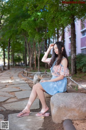 A woman leaning against a column in a park.