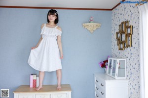 A woman sitting on top of a white dresser.