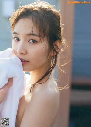 A woman in a white shirt and white panties posing by a pool.