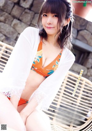 A woman in a bikini and a hat posing for a picture.