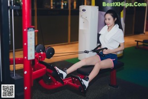 A woman sitting on the floor in a gym.