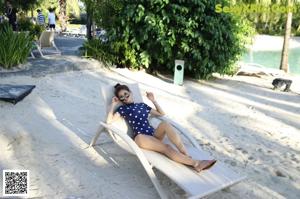 A woman in a bathing suit eating an apple.