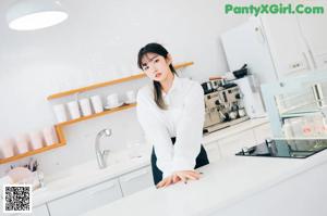 A woman standing in a kitchen next to a sink.