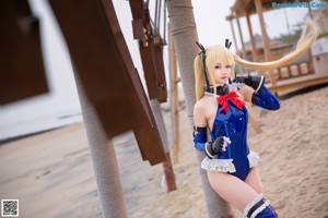 A woman in a blue and red outfit sitting on the sand.