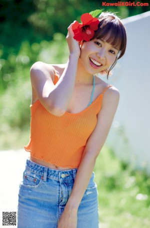 A woman in a blue bikini top and denim shorts sitting on a kitchen counter.