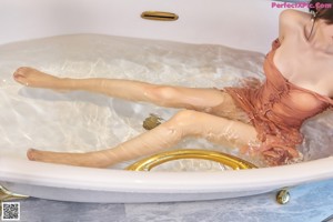 A woman in a brown dress standing in a bathtub.