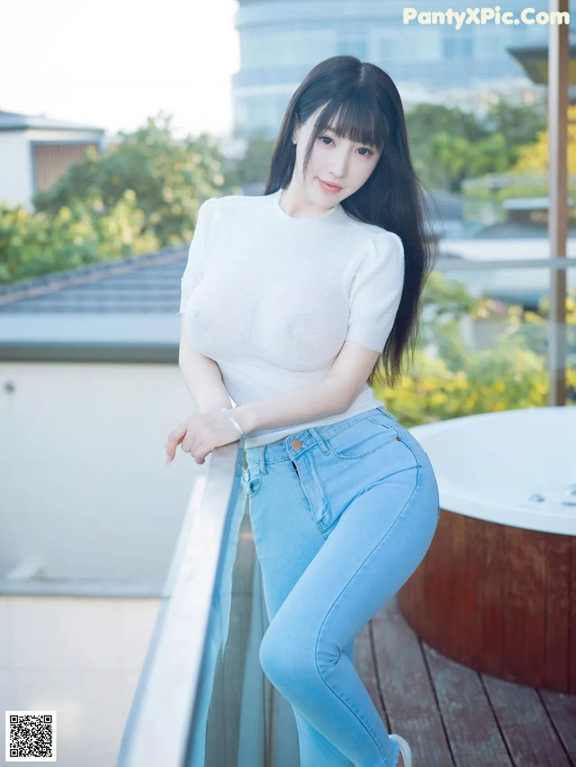 A woman in a white shirt and blue jeans posing for a picture.