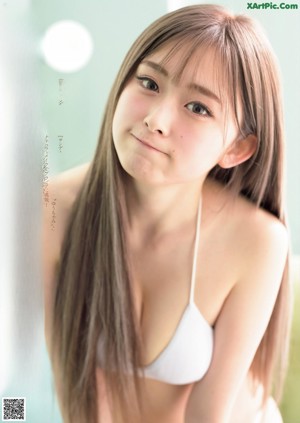 A woman in a bikini blowing bubbles in front of a wooden wall.