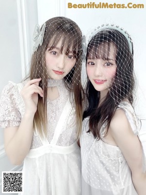Two young women wearing white dresses and a birdcage veil.