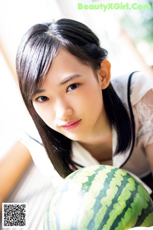 A woman sitting on top of a watermelon next to a window.