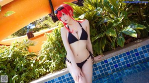 A woman in a black bikini sitting on the edge of a pool.