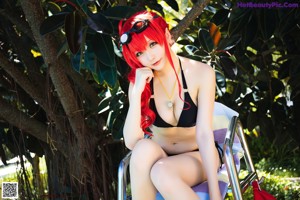 A woman in a bikini sitting by a swimming pool.