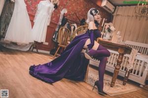 A woman in a purple dress sitting on a wooden floor.