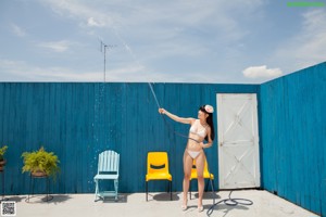 A woman in a white bikini sitting on a yellow chair.