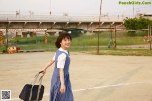 A young woman in a blue dress standing on a street.