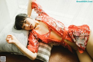 A woman in a red kimono sitting on the floor.