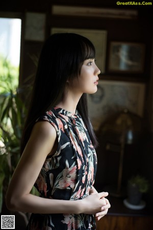 A woman in a floral dress sitting on the floor.