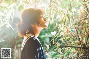 A woman in a school uniform leaning against a tree stump.