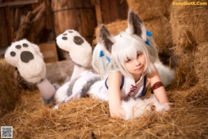 A woman in a bunny costume sitting on a pile of hay.