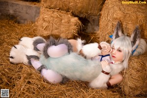 A woman in a bunny costume sitting on a pile of hay.