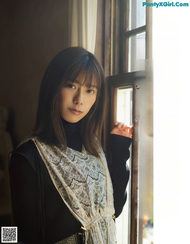 A woman standing in front of a window wearing a scarf.