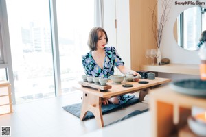 A woman sitting on the floor next to a table.