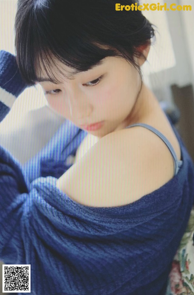 A woman in a blue dress sitting on a bed.