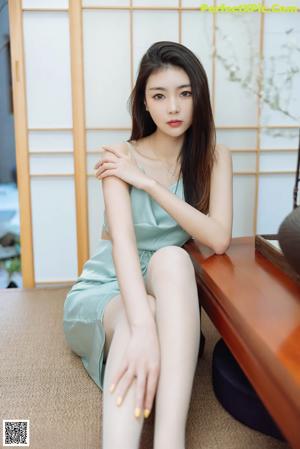 A woman sitting on the floor next to a table with a cup of tea.