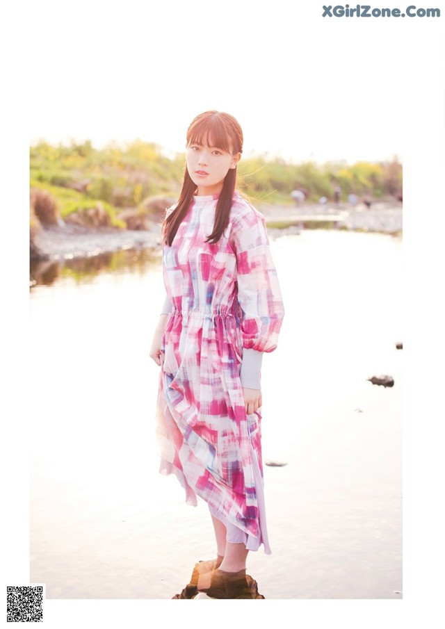 A woman standing on a rock by the water.