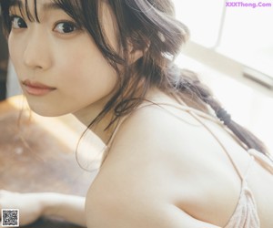 A woman in a white lingerie sitting in a bathtub.