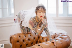 A woman with tattoos sitting on the floor in a wedding dress.