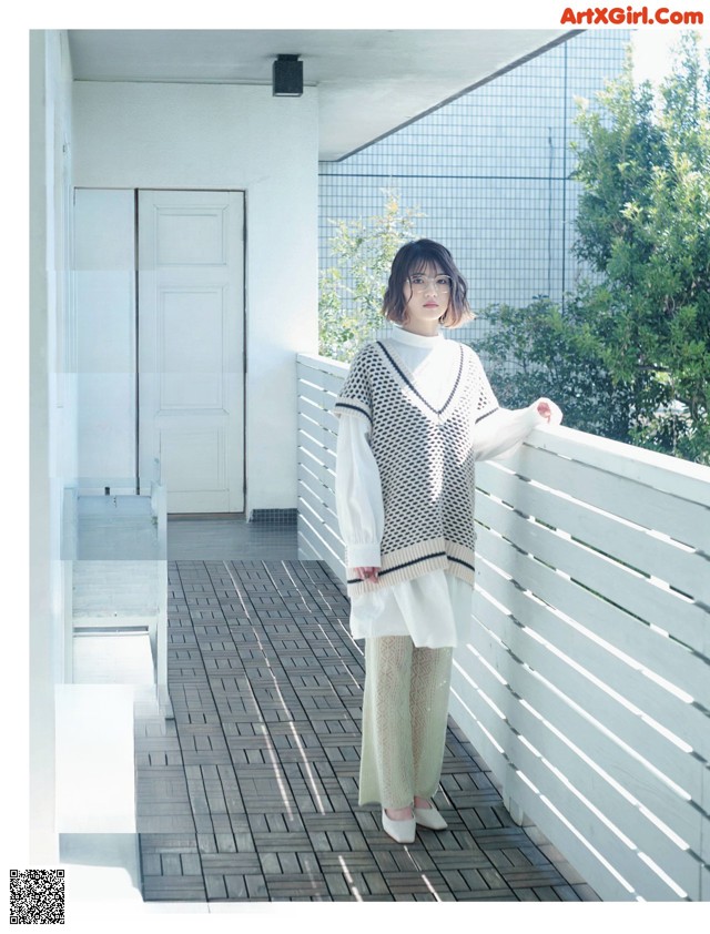 A woman standing on a balcony next to a white fence.