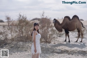 A woman standing in the middle of a dirt road.